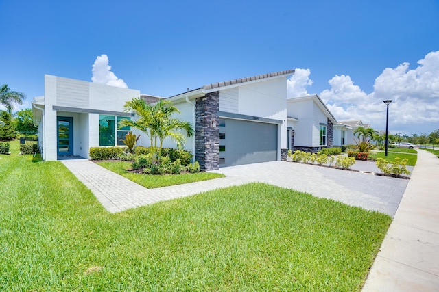 11695 SW Viridian Blvd, Port Saint Lucie, FL 34987 - contemporary house with stone siding, a front lawn, and decorative driveway
