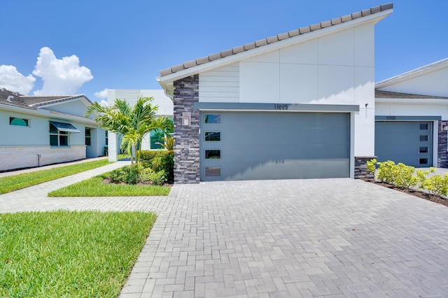 11695 SW Viridian Blvd, Port Saint Lucie, FL 34987 - view of front of house with driveway, stone siding, an attached garage, and a tile roof