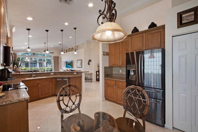 7052 Cataluna Cir, Delray Beach, FL 33446 - kitchen featuring stainless steel appliances, brown cabinetry, tasteful backsplash, light tile patterned floors, and crown molding