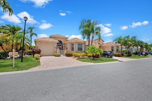 7052 Cataluna Cir, Delray Beach, FL 33446 - mediterranean / spanish-style home with a tiled roof, decorative driveway, an attached garage, stucco siding, and a front yard