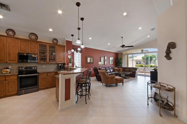 7052 Cataluna Cir, Delray Beach, FL 33446 - kitchen with appliances with stainless steel finishes, brown cabinets, a kitchen breakfast bar, open floor plan, and decorative backsplash