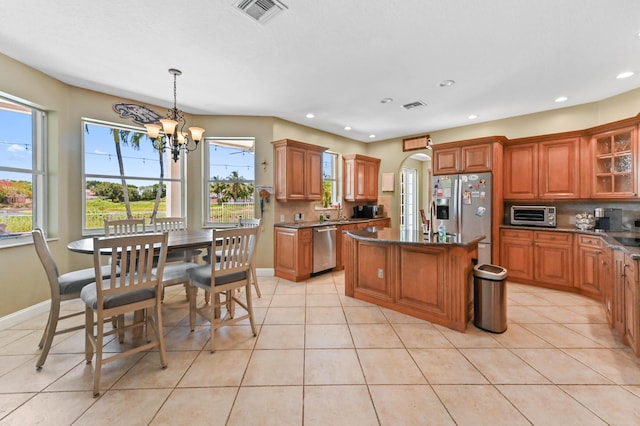 7486 Greenville Cir, Lake Worth, FL 33467 - kitchen with appliances with stainless steel finishes, a chandelier, a center island, brown cabinets, and glass insert cabinets
