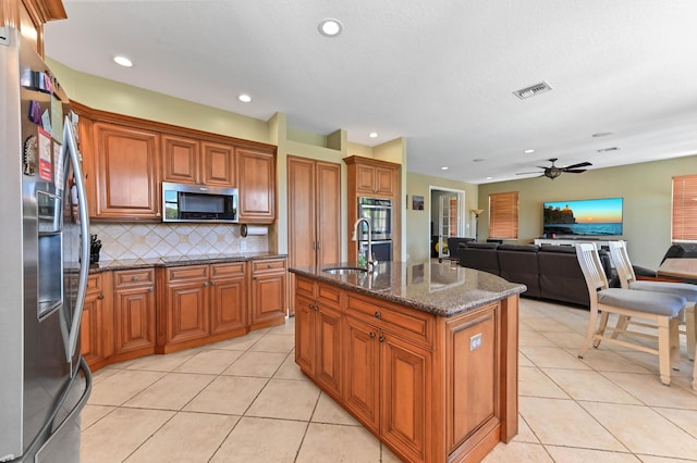 7486 Greenville Cir, Lake Worth, FL 33467 - kitchen featuring stainless steel appliances, brown cabinetry, a ceiling fan, open floor plan, and light tile patterned floors