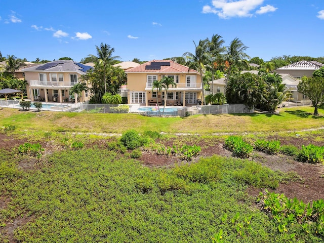7486 Greenville Cir, Lake Worth, FL 33467 - back of house with roof mounted solar panels, an outdoor pool, stucco siding, and a fenced backyard