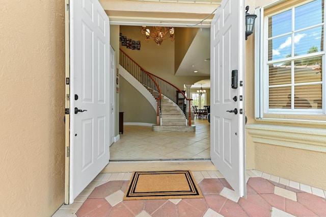 7486 Greenville Cir, Lake Worth, FL 33467 - entryway featuring a chandelier, a textured wall, inlaid floor details, light tile patterned floors, and stairs