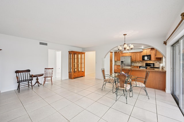 7 Greenway N Unit 111, Royal Palm Beach, FL 33411 - dining space featuring arched walkways, a chandelier, and light tile patterned flooring