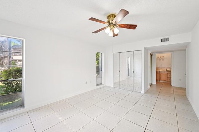 7 Greenway N Unit 111, Royal Palm Beach, FL 33411 - unfurnished bedroom featuring multiple windows, light tile patterned floors, a ceiling fan, and a closet