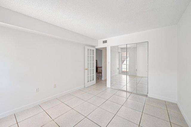7 Greenway N Unit 111, Royal Palm Beach, FL 33411 - unfurnished room featuring french doors, light tile patterned floors, and a textured ceiling