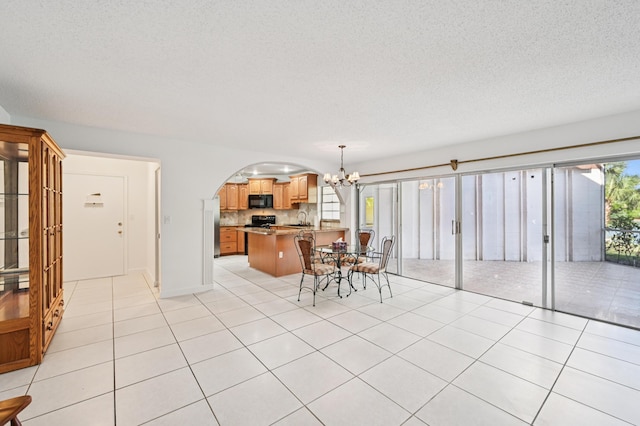 7 Greenway N Unit 111, Royal Palm Beach, FL 33411 - dining area featuring a chandelier, a textured ceiling, light tile patterned floors, and arched walkways