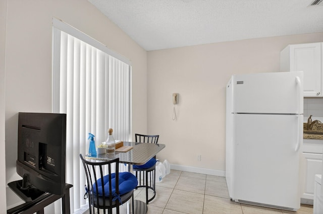 13984 Via Flora Unit B, Delray Beach, FL 33484 - kitchen with freestanding refrigerator, white cabinetry, light tile patterned floors, and a textured ceiling