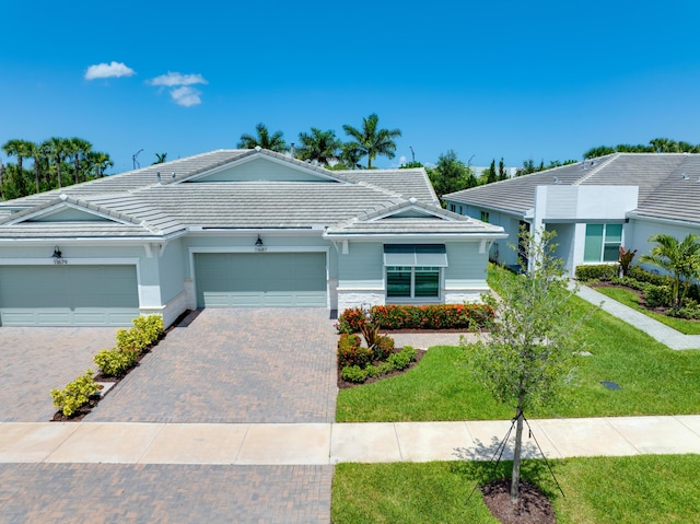 11687 SW Viridian Blvd, Port Saint Lucie, FL 34987 - view of front of home with a tile roof, an attached garage, a front yard, and decorative driveway