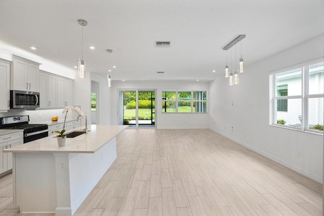 11687 SW Viridian Blvd, Port Saint Lucie, FL 34987 - kitchen with stainless steel appliances, open floor plan, recessed lighting, light countertops, and light wood-style floors