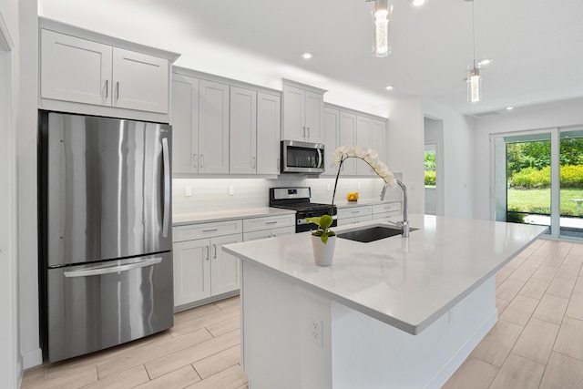 11687 SW Viridian Blvd, Port Saint Lucie, FL 34987 - kitchen with appliances with stainless steel finishes, decorative backsplash, an island with sink, light countertops, and pendant lighting