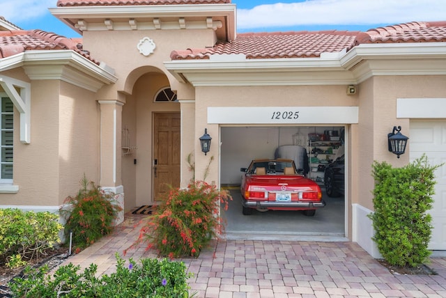 12025 Aviles Cir, Palm Beach Gardens, FL 33418 - doorway to property featuring a tile roof, stucco siding, driveway, and an attached garage