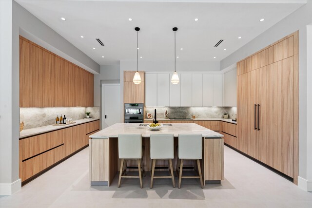 2265 NE 30th Ct, Lighthouse Point, FL 33064 - kitchen with modern cabinets, a kitchen island with sink, a breakfast bar, tasteful backsplash, and recessed lighting