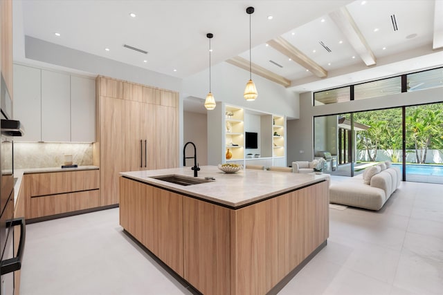 2265 NE 30th Ct, Lighthouse Point, FL 33064 - kitchen with modern cabinets, beamed ceiling, backsplash, open floor plan, and an island with sink