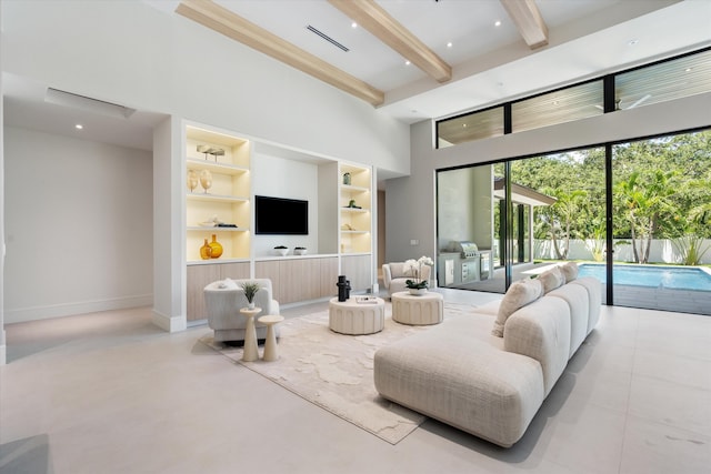 2265 NE 30th Ct, Lighthouse Point, FL 33064 - living area featuring built in shelves, beam ceiling, a high ceiling, and concrete floors