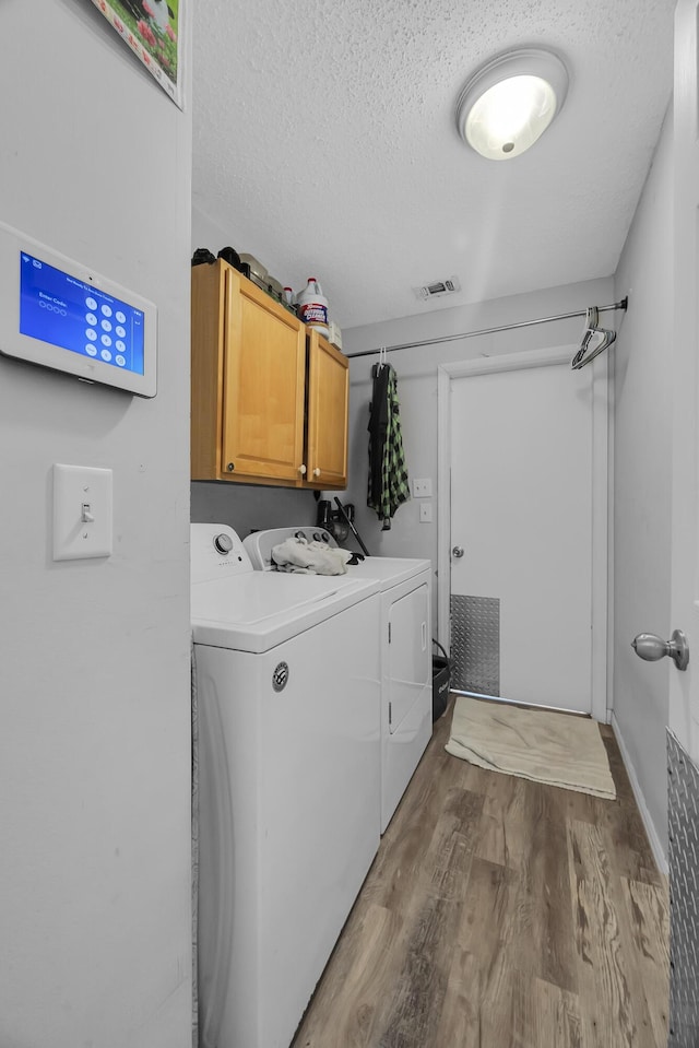 356 SW Grimaldo Ter, Port Saint Lucie, FL 34984 - laundry area featuring cabinet space, washer and clothes dryer, wood finished floors, and a textured ceiling