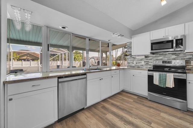 356 SW Grimaldo Ter, Port Saint Lucie, FL 34984 - kitchen featuring stainless steel appliances, vaulted ceiling, backsplash, light stone countertops, and white cabinets