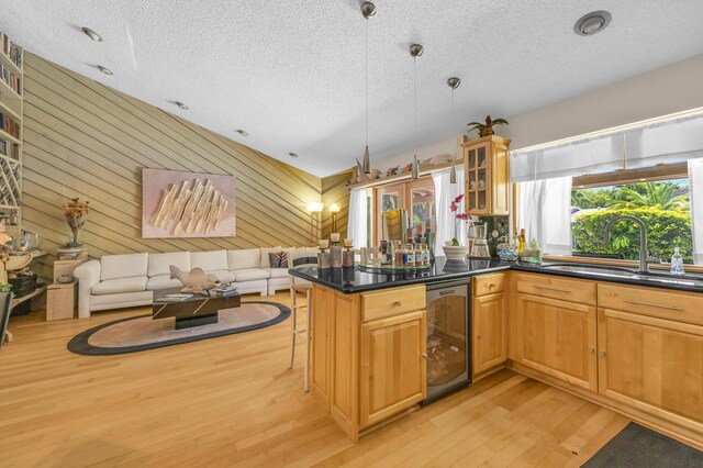 9070 NW 16th St, Plantation, FL 33322 - kitchen featuring wine cooler, a textured ceiling, light wood finished floors, open floor plan, and glass insert cabinets