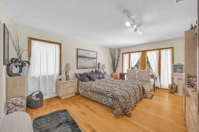 9070 NW 16th St, Plantation, FL 33322 - bedroom with light wood-style floors, a textured ceiling, and rail lighting