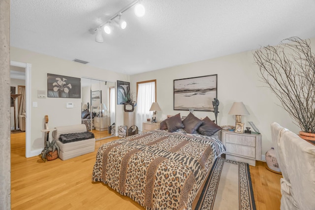 9070 NW 16th St, Plantation, FL 33322 - bedroom with a textured ceiling, light wood-style flooring, a closet, and rail lighting