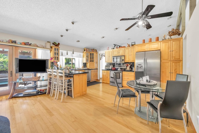 9070 NW 16th St, Plantation, FL 33322 - kitchen with appliances with stainless steel finishes, dark countertops, a textured ceiling, glass insert cabinets, and a kitchen breakfast bar