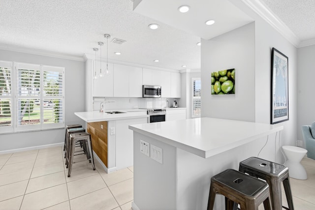5086 Prairie Dunes Village Cir, Lake Worth, FL 33463 - kitchen with appliances with stainless steel finishes, a textured ceiling, a kitchen breakfast bar, ornamental molding, and light countertops