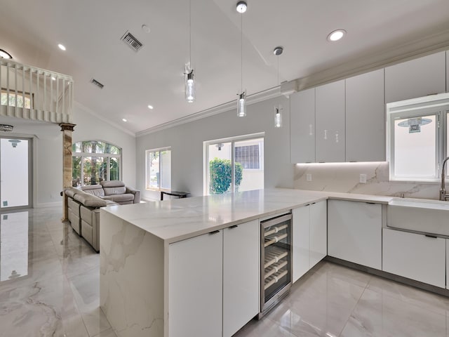 10889 Fillmore Dr, Boynton Beach, FL 33437 - kitchen featuring wine cooler, light marble finish flooring, ornamental molding, lofted ceiling, and a peninsula