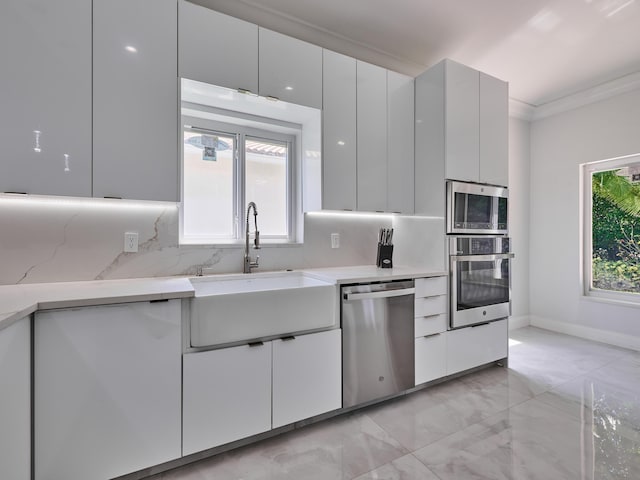 10889 Fillmore Dr, Boynton Beach, FL 33437 - kitchen with appliances with stainless steel finishes, healthy amount of natural light, light marble finish floors, decorative backsplash, and ornamental molding