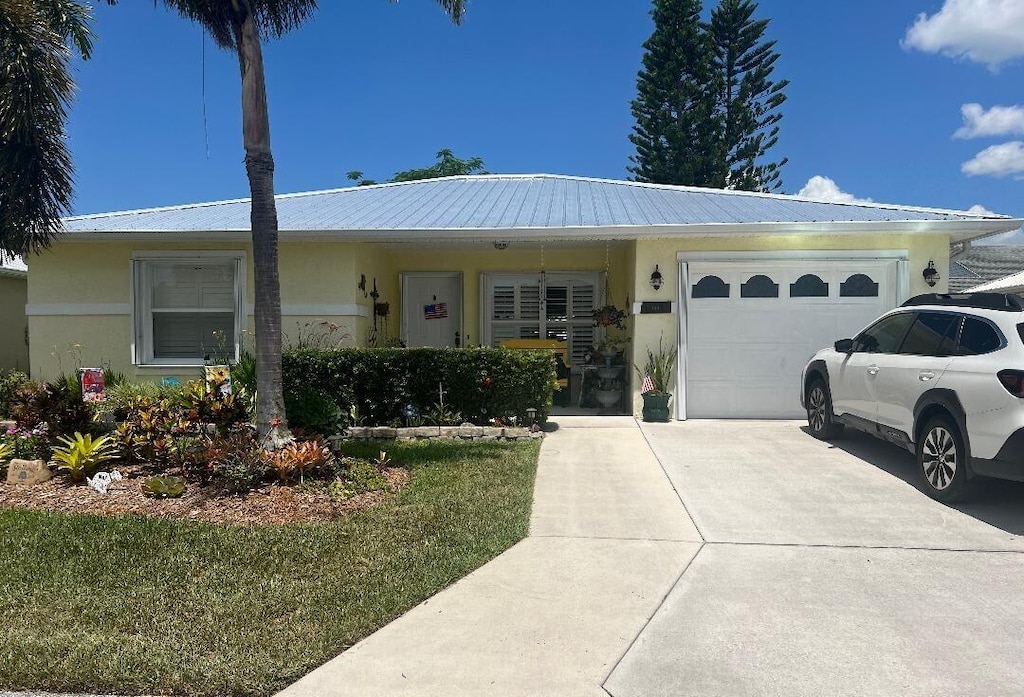 6661 Nuevo Lagos, Fort Pierce, FL 34951 - single story home with an attached garage, driveway, a metal roof, and stucco siding