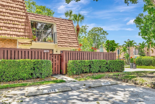 3675 SW Sunset Trace Cir, Palm City, FL 34990 - view of side of home featuring a gate, uncovered parking, brick siding, and mansard roof