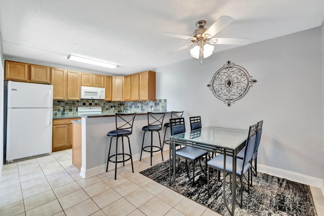 3675 SW Sunset Trace Cir, Palm City, FL 34990 - kitchen with white appliances, decorative backsplash, light tile patterned floors, a ceiling fan, and a textured ceiling