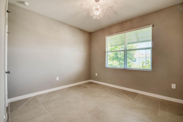 1878 NE Ocean Dunes Dr, Jensen Beach, FL 34957 - empty room with a smoke detector, a chandelier, and light tile patterned flooring