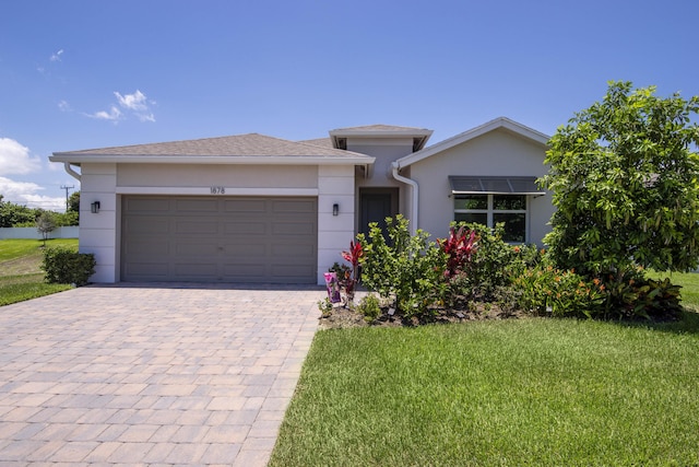 1878 NE Ocean Dunes Dr, Jensen Beach, FL 34957 - view of front facade featuring a garage, decorative driveway, stucco siding, and a front lawn
