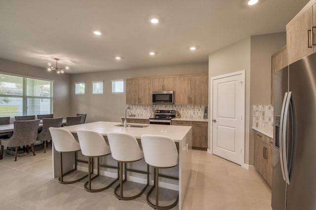 1878 NE Ocean Dunes Dr, Jensen Beach, FL 34957 - kitchen with appliances with stainless steel finishes, decorative backsplash, a breakfast bar area, a kitchen island with sink, and recessed lighting