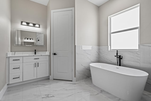 3257 SE Snow Rd, Port Saint Lucie, FL 34984 - bathroom with marble finish floors, vanity, a soaking tub, a wainscoted wall, and tile walls