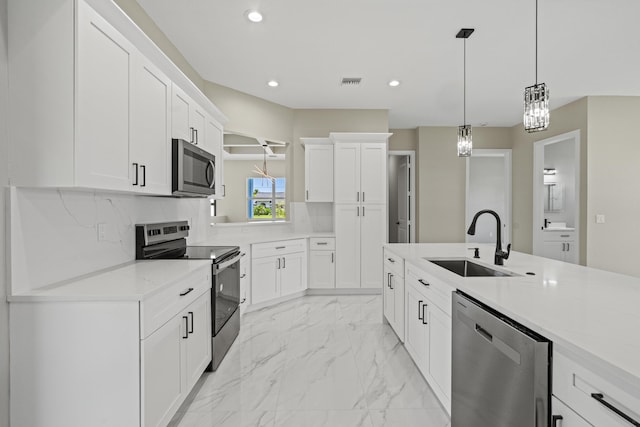 3257 SE Snow Rd, Port Saint Lucie, FL 34984 - kitchen with stainless steel appliances, recessed lighting, light marble finish flooring, white cabinetry, and pendant lighting