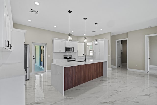 3257 SE Snow Rd, Port Saint Lucie, FL 34984 - kitchen with appliances with stainless steel finishes, light countertops, an island with sink, light marble finish flooring, and white cabinetry