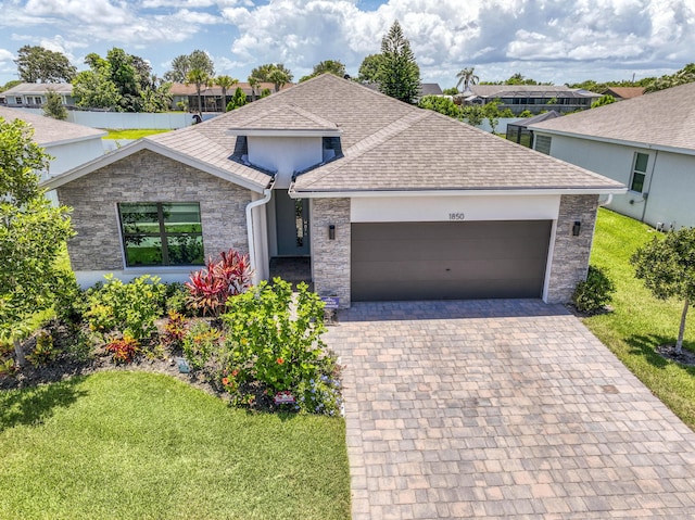 1850 NE Ocean Dunes Dr, Jensen Beach, FL 34957 - single story home featuring a front yard, roof with shingles, an attached garage, and stone siding