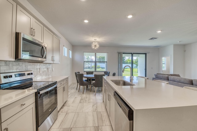 1850 NE Ocean Dunes Dr, Jensen Beach, FL 34957 - kitchen featuring appliances with stainless steel finishes, light marble finish floors, recessed lighting, light countertops, and a center island with sink