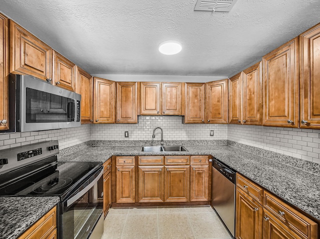 1303 NW 2nd St, Delray Beach, FL 33444 - kitchen with appliances with stainless steel finishes, brown cabinetry, light tile patterned floors, tasteful backsplash, and dark stone counters