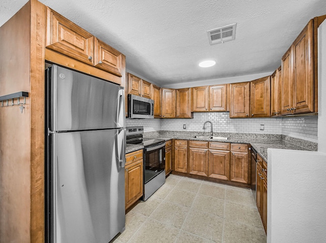 1303 NW 2nd St, Delray Beach, FL 33444 - kitchen with stainless steel appliances, brown cabinets, tasteful backsplash, dark stone counters, and a textured ceiling
