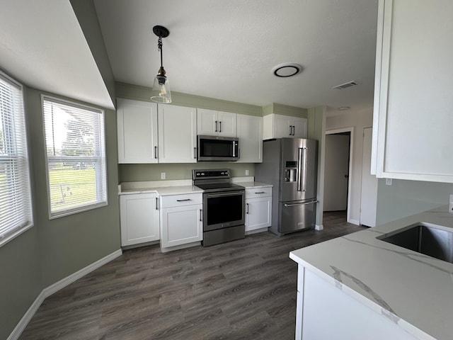 226 SW Statler Ave, Port Saint Lucie, FL 34984 - kitchen featuring stainless steel appliances, white cabinets, dark wood-type flooring, and decorative light fixtures