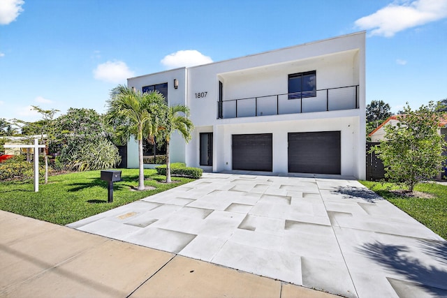 1807 NE 18th St, Fort Lauderdale, FL 33305 - contemporary house featuring stucco siding, driveway, a balcony, an attached garage, and a front yard