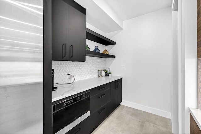 1807 NE 18th St, Fort Lauderdale, FL 33305 - kitchen with dark cabinets, open shelves, decorative backsplash, refrigerator, and light stone countertops