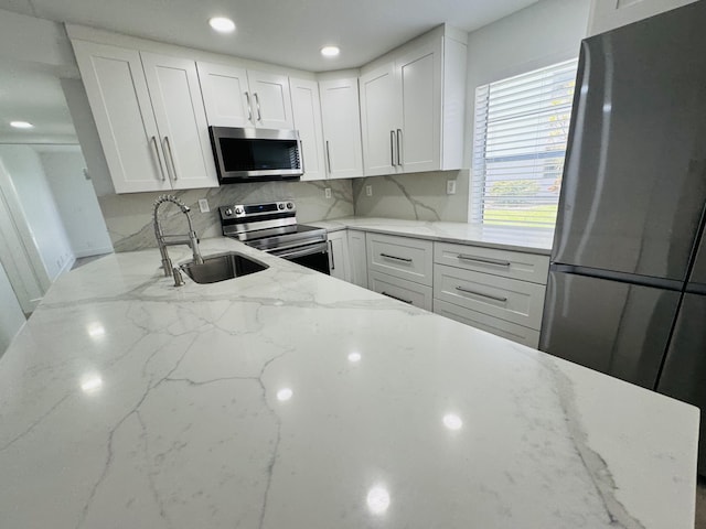 970 Normandy U, Delray Beach, FL 33484 - kitchen with stainless steel appliances, white cabinetry, light stone counters, decorative backsplash, and recessed lighting