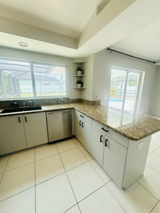 6455 NW Foxglove St, Port Saint Lucie, FL 34986 - kitchen with dishwasher, a peninsula, open shelves, light stone counters, and light tile patterned flooring