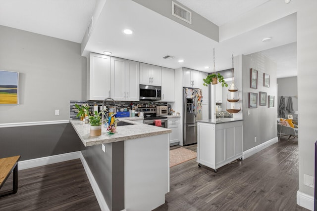 274 Murray Ct, Jupiter, FL 33458 - kitchen with stainless steel appliances, a peninsula, dark wood-style flooring, light countertops, and decorative backsplash