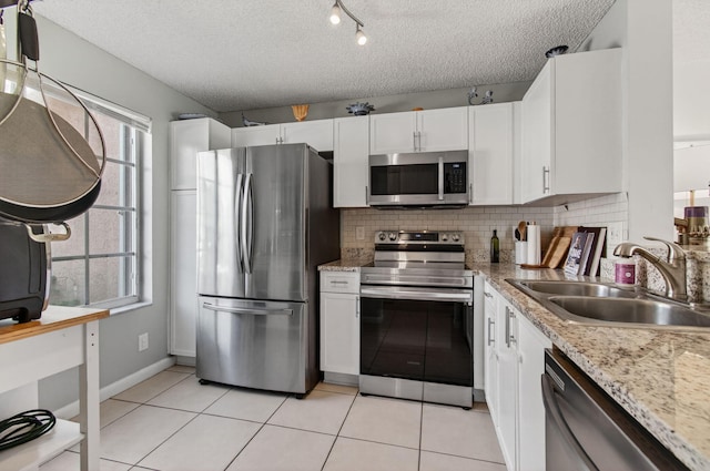 9931 Kamena Cir, Boynton Beach, FL 33436 - kitchen featuring appliances with stainless steel finishes, white cabinetry, a textured ceiling, decorative backsplash, and light tile patterned floors